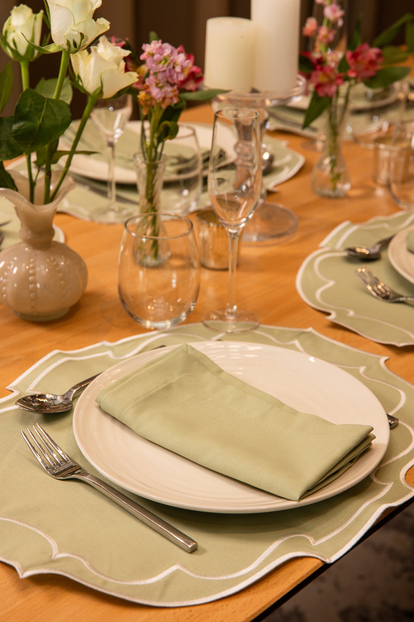 Top Tables Taylor Placemat & Napkin in Sage Green cotton, with scalloped trim, styled on a refined table with florals and candles.