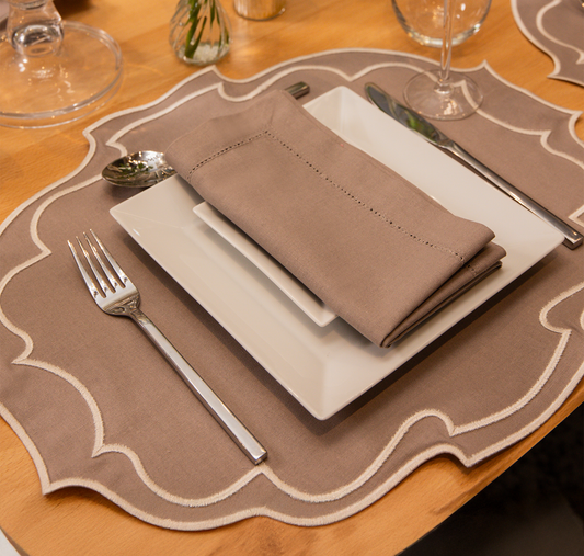Top Tables Taylor Placemat & Napkin in Latte, featuring scalloped edges and subtle stitching for an elegant table setting.